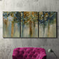 Three-panel canvas wall art featuring earth toned abstract leaf textures, displayed in a living room above a suede accent chair.