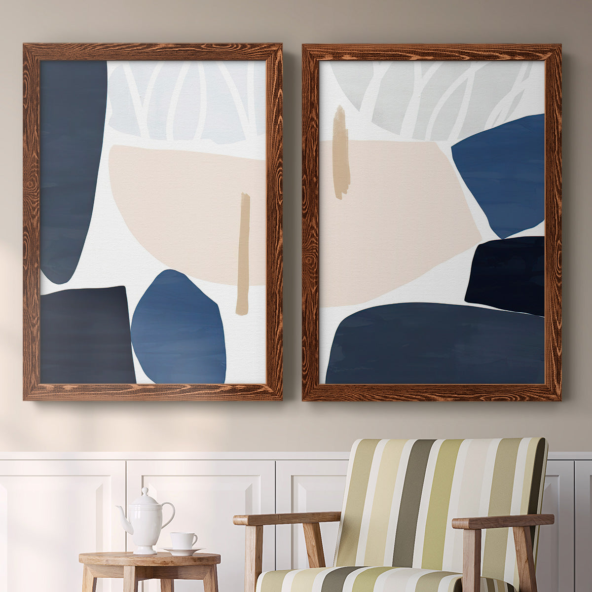 Set of two maple barnwood framed canvas prints depicting two minimalist color-block abstracts featuring large navy cream and beige organic geometric shapes above a sideboard in a cozy sitting room.