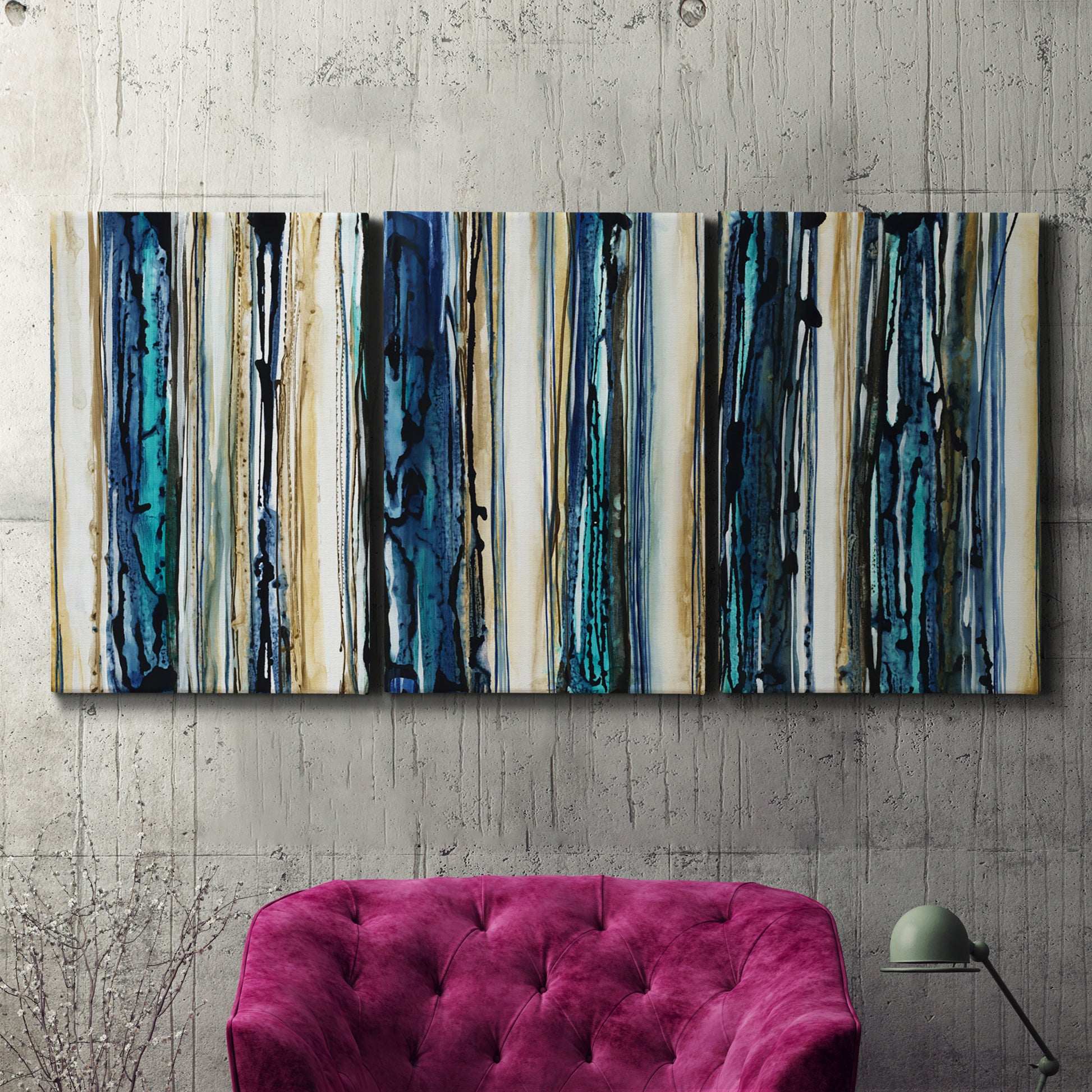Three-panel canvas wall art featuring vertical blue abstract streaks, displayed in a living room above a suede accent chair.