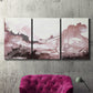 Three-panel canvas wall art featuring soft pink abstract scenic layers, displayed in a living room above a suede accent chair.