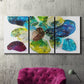 Three-panel canvas wall art featuring expressive abstract color interpretations, displayed in a living room above a suede accent chair.
