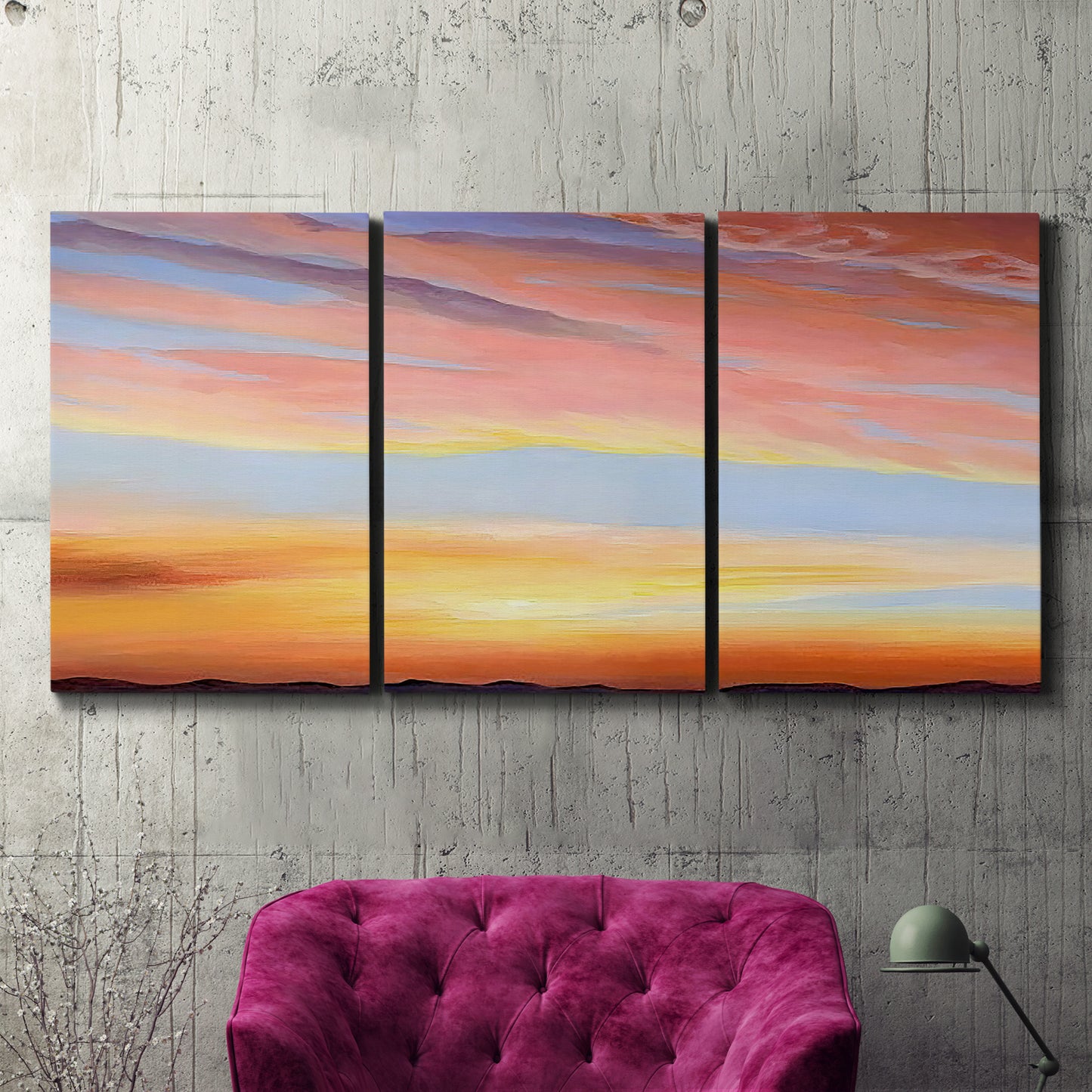 Three-panel canvas wall art featuring glowing sunset sky over landscape, displayed in a living room above a suede accent chair.