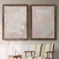 Set of two walnut barnwood framed canvas prints depicting two minimalist color-field abstracts featuring soft blush and white painterly fields above a sideboard in a cozy sitting room.