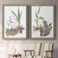 Set of two gray barnwood framed canvas prints depicting two whimsical botanical animal illustrations featuring cats tucked among collections of potted houseplants above a sideboard in a cozy sitting room.