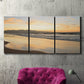 Three-panel canvas wall art featuring quiet tropical shoreline at low tide, displayed in a living room above a suede accent chair.