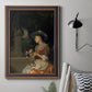 Classical interior scene of a woman weaving flowers by Godfried Schalcken in an ornate bronzed mahogany wood frame displayed in a neutral interior setting.