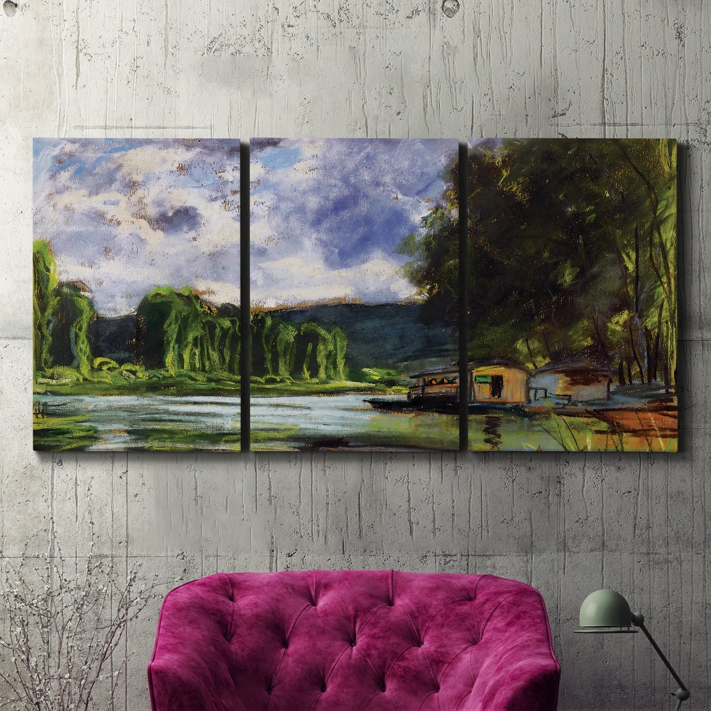 Three-panel canvas wall art featuring riverbank landscape near village, displayed in a living room above a suede accent chair.
