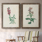 Set of two walnut barnwood framed canvas prints depicting two vintage botanical studies of flowering stems with detailed green leaves on aged cream paper above a sideboard in a cozy sitting room.