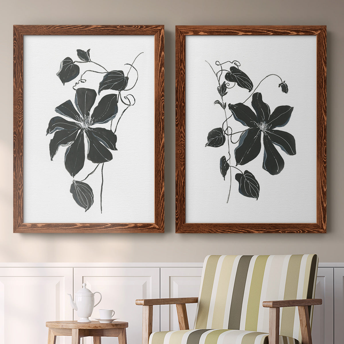 Set of two maple barnwood framed canvas prints depicting two minimalist botanical prints featuring black leafy vine silhouettes above a sideboard in a cozy sitting room.