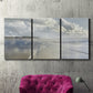 Three-panel canvas wall art featuring endless beach meeting ocean horizon, displayed in a living room above a suede accent chair.