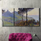Three-panel canvas wall art featuring village church at sunset, displayed in a living room above a suede accent chair.