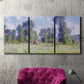 Three-panel canvas wall art featuring poppy field near garden village, displayed in a living room above a suede accent chair.