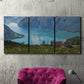 Three-panel canvas wall art featuring symmetrical water reflections with trees, displayed in a living room above a suede accent chair.