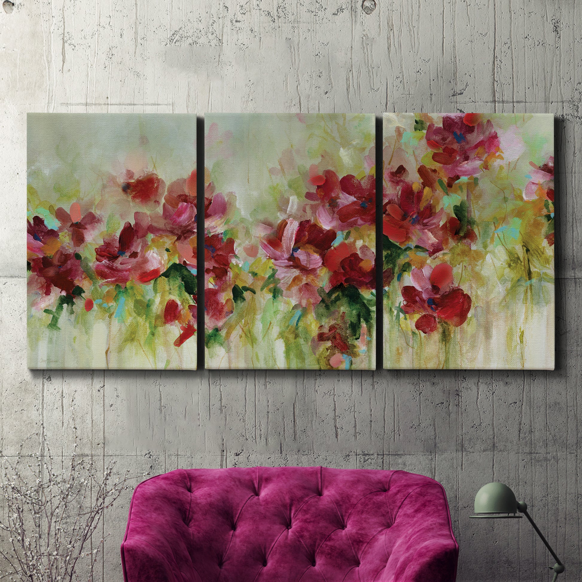 Three-panel canvas wall art featuring colorful floral garden composition, displayed in a living room above a suede accent chair.