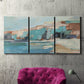 Three-panel canvas wall art featuring coastal shoreline with soft waves, displayed in a living room above a suede accent chair.