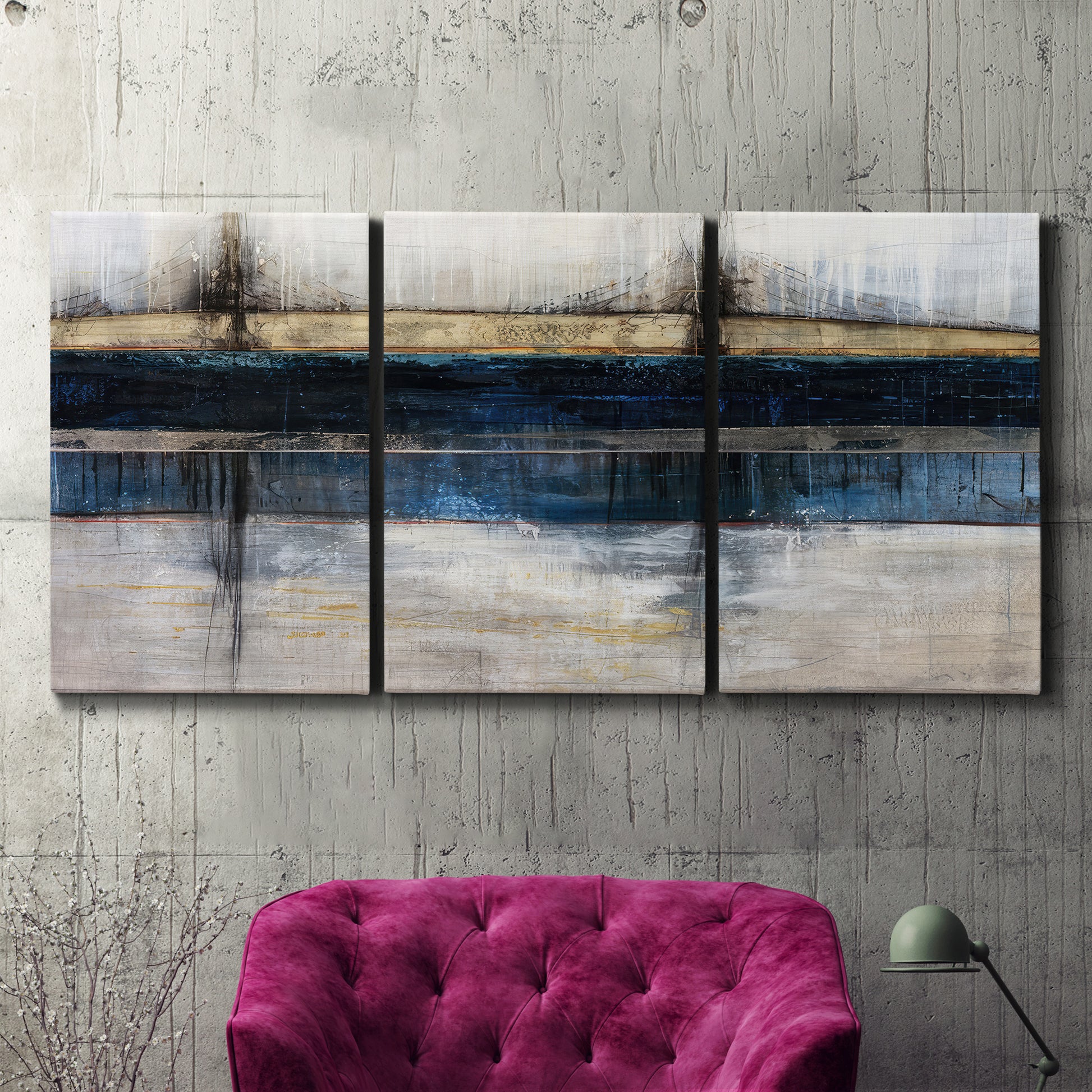 Three-panel canvas wall art featuring abstract blue urban composition, displayed in a living room above a suede accent chair.