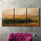 Three-panel canvas wall art featuring soft abstract evening light, displayed in a living room above a suede accent chair.