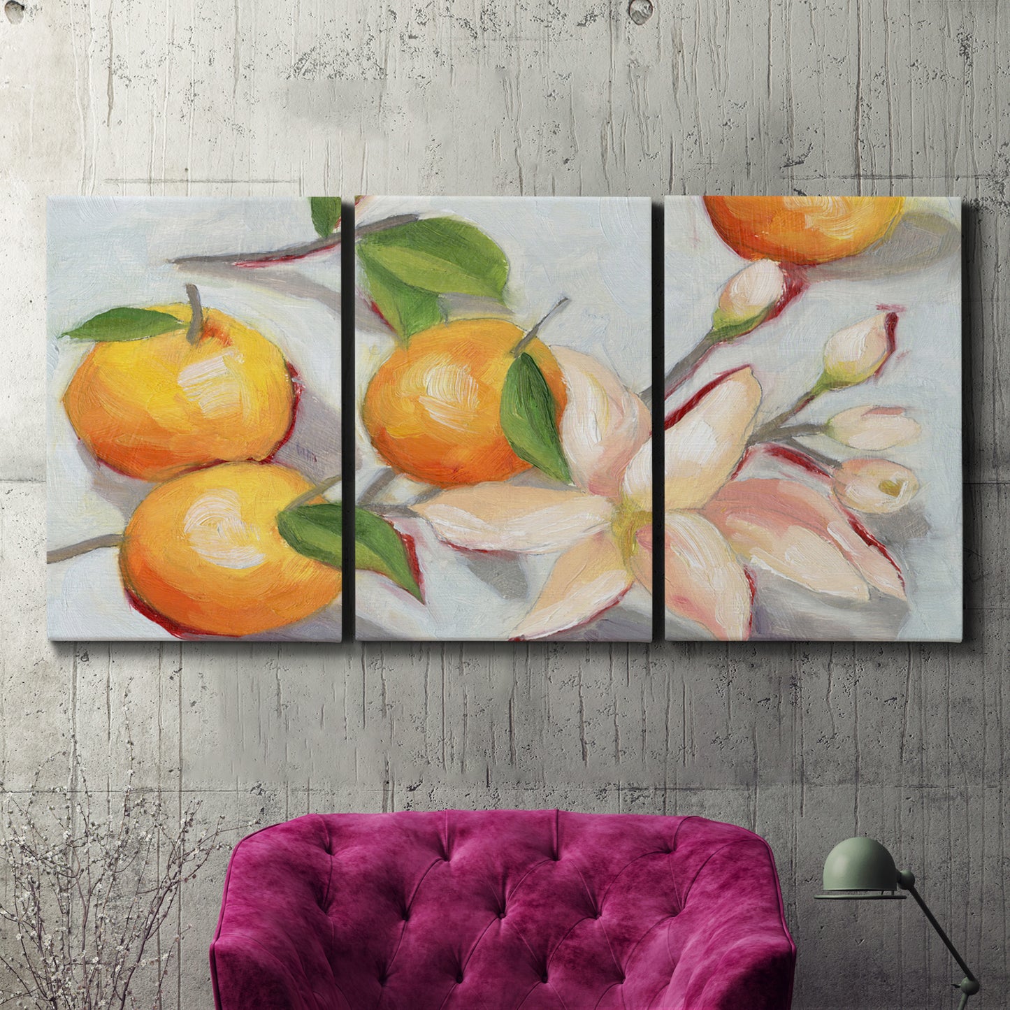Three-panel canvas wall art featuring bright tangerine still life blossoms, displayed in a living room above a suede accent chair.