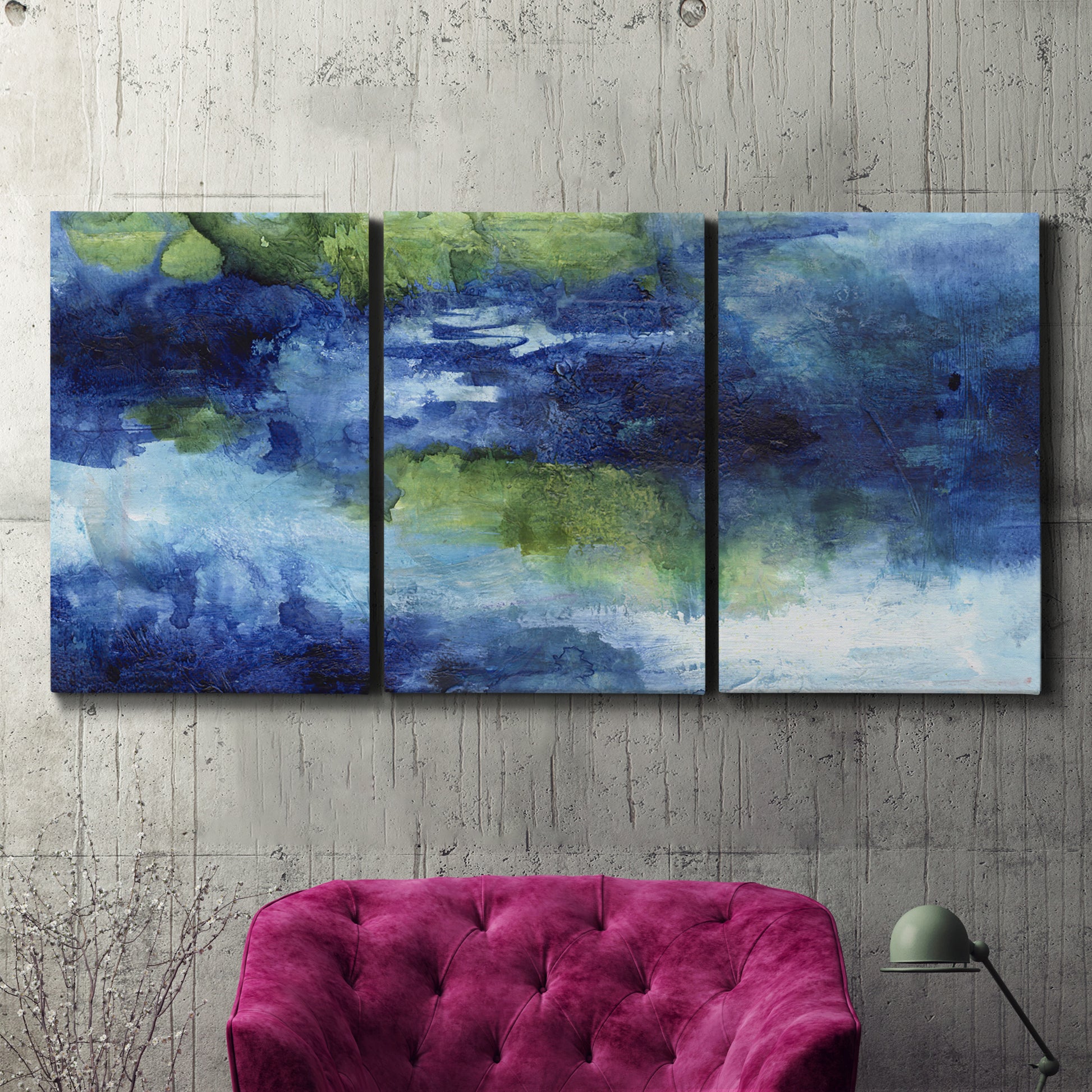 Three-panel canvas wall art featuring flowing blue abstract watercolor, displayed in a living room above a suede accent chair.
