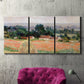Three-panel canvas wall art featuring haystacks arranged in rural field, displayed in a living room above a suede accent chair.