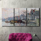 Three-panel canvas wall art featuring historic canal view with boats, displayed in a living room above a suede accent chair.