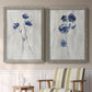 Set of two gray barnwood framed canvas prints depicting two rustic monochrome botanical paintings featuring blue wildflower stems on weathered neutral paper above a sideboard in a cozy sitting room.