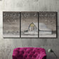 Three-panel canvas wall art featuring rustic winter holiday text art, displayed in a living room above a suede accent chair.