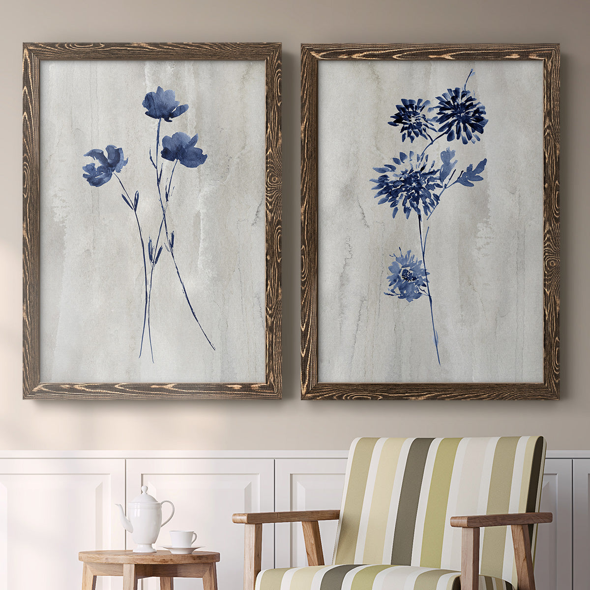 Set of two walnut barnwood framed canvas prints depicting two rustic monochrome botanical paintings featuring blue wildflower stems on weathered neutral paper above a sideboard in a cozy sitting room.