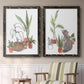 Set of two black barnwood framed canvas prints depicting two whimsical botanical animal illustrations featuring cats tucked among collections of potted houseplants above a sideboard in a cozy sitting room.