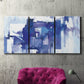 Three-panel canvas wall art featuring abstract urban street scene, displayed in a living room above a suede accent chair.