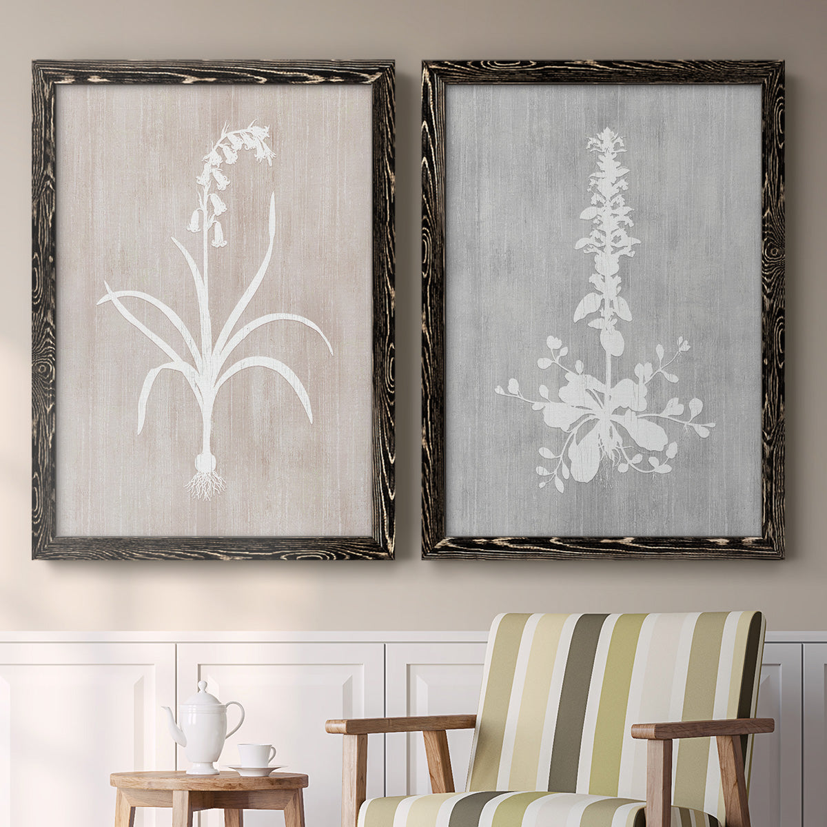 Set of two black barnwood framed canvas prints depicting two rustic minimalist botanical prints featuring white botanical silhouettes on softly weathered neutral backgrounds above a sideboard in a cozy sitting room.