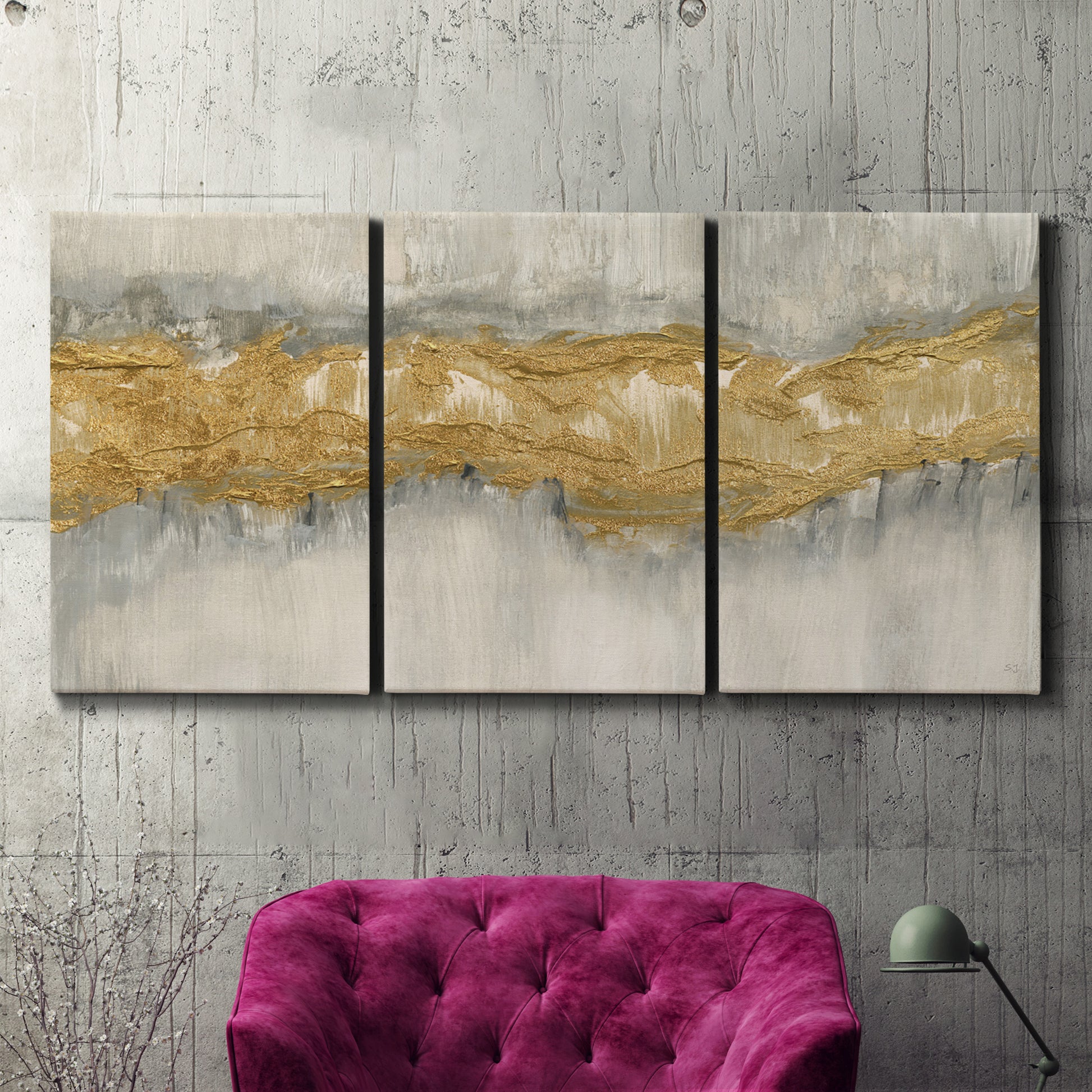Three-panel canvas wall art featuring flowing abstract golden tones, displayed in a living room above a suede accent chair.