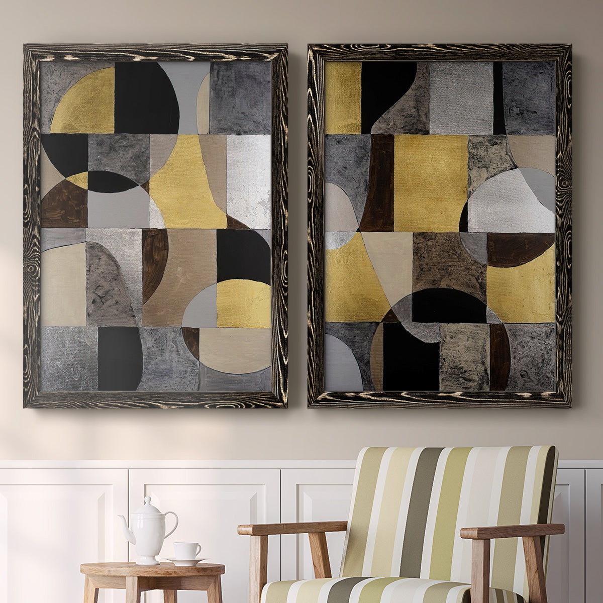 Set of two black barnwood framed canvas prints depicting two structured modern abstracts featuring interlocking black gray cream and gold geometric sections above a sideboard in a cozy sitting room.