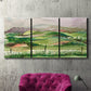 Three-panel canvas wall art featuring rainy landscape with soft atmosphere, displayed in a living room above a suede accent chair.