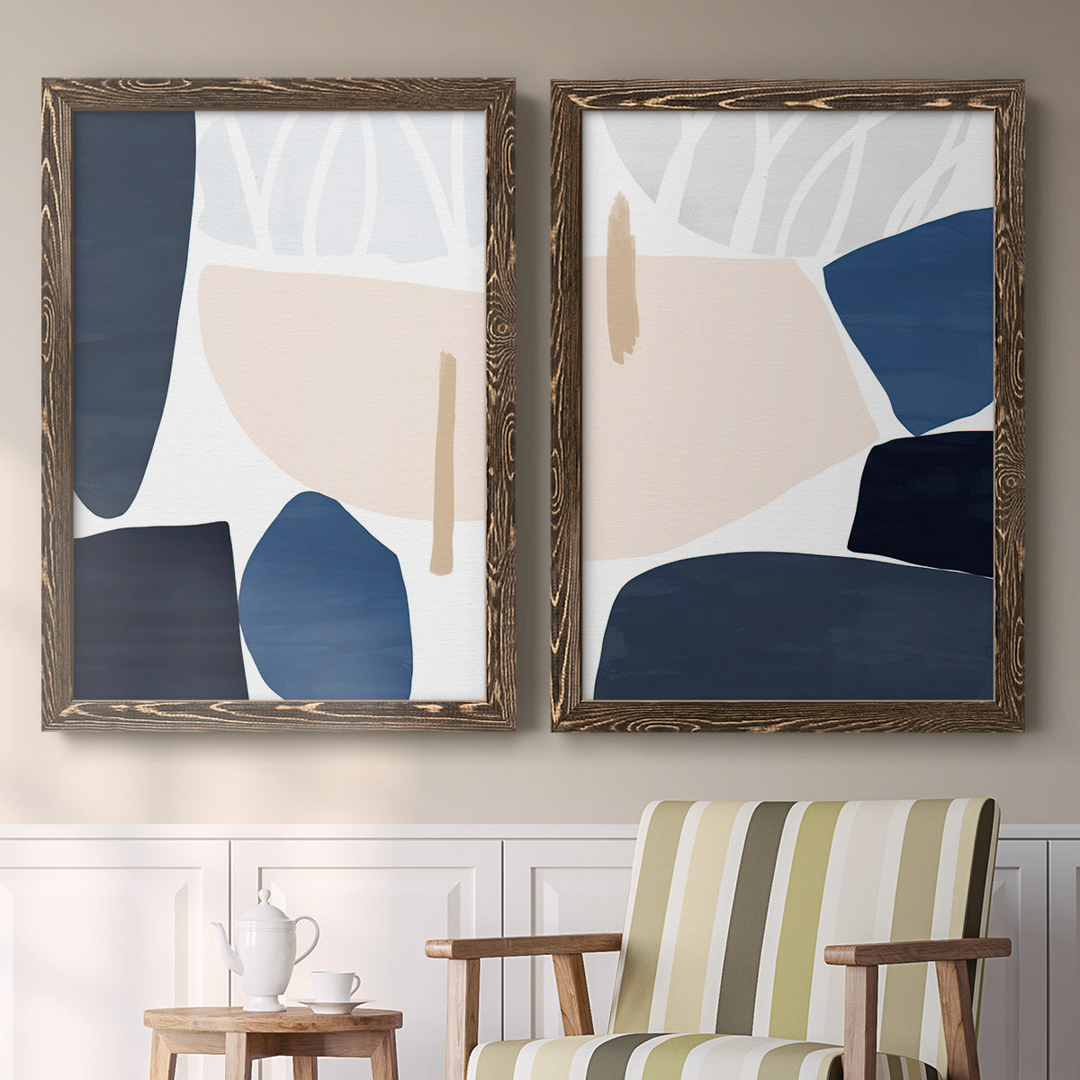 Set of two walnut barnwood framed canvas prints depicting two minimalist color-block abstracts featuring large navy cream and beige organic geometric shapes above a sideboard in a cozy sitting room.