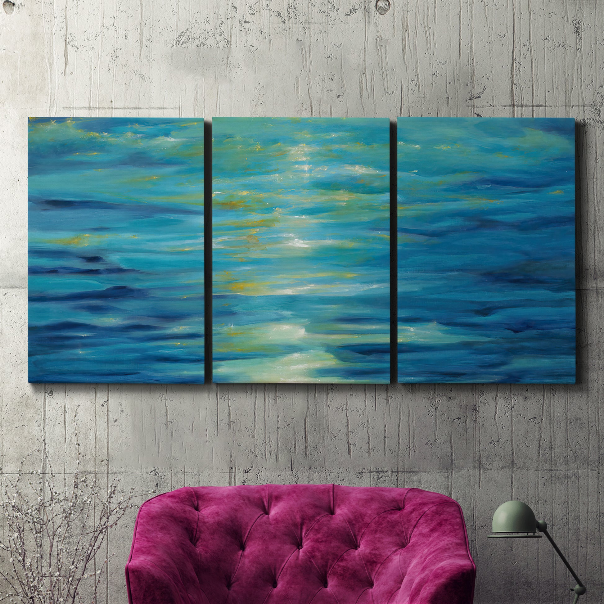 Three-panel canvas wall art featuring deep blue ocean water abstraction, displayed in a living room above a suede accent chair.