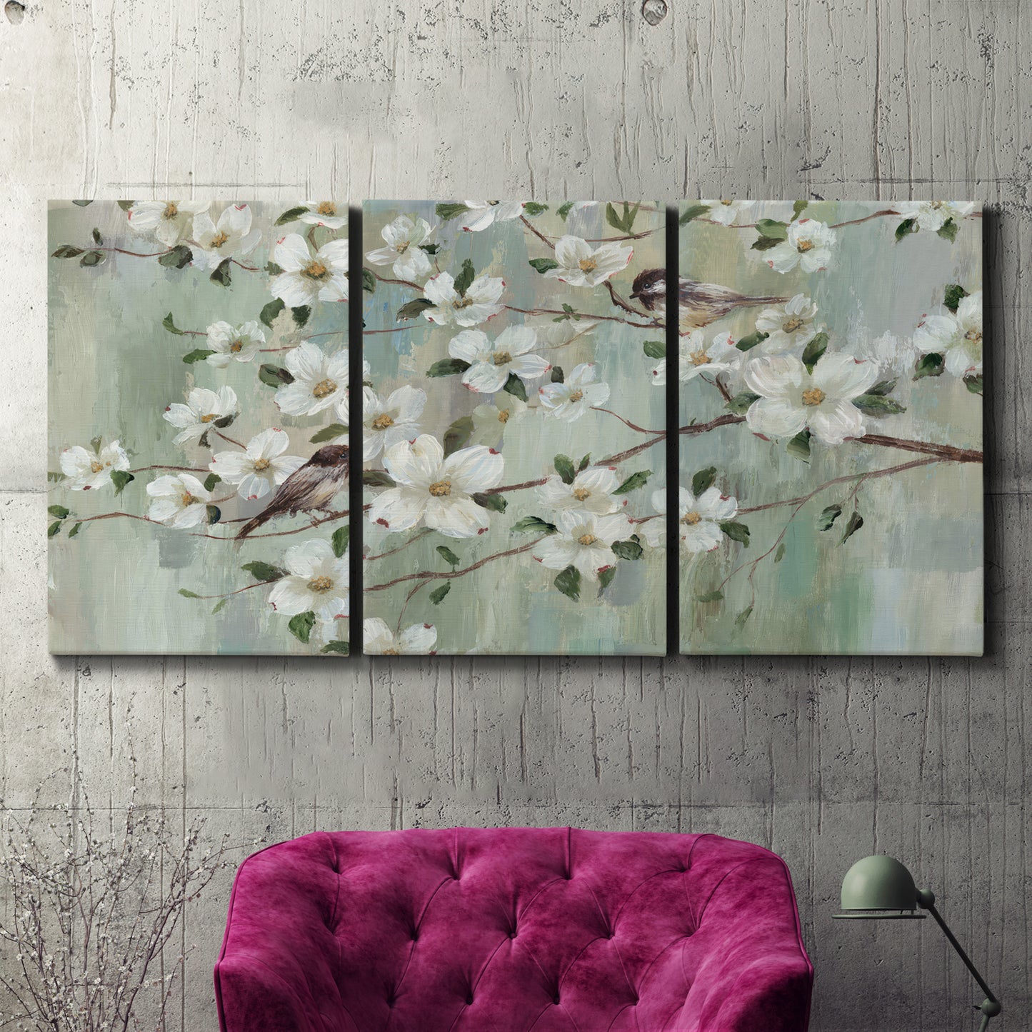 Three-panel canvas wall art featuring delicate spring blossoms with birds, displayed in a living room above a suede accent chair.
