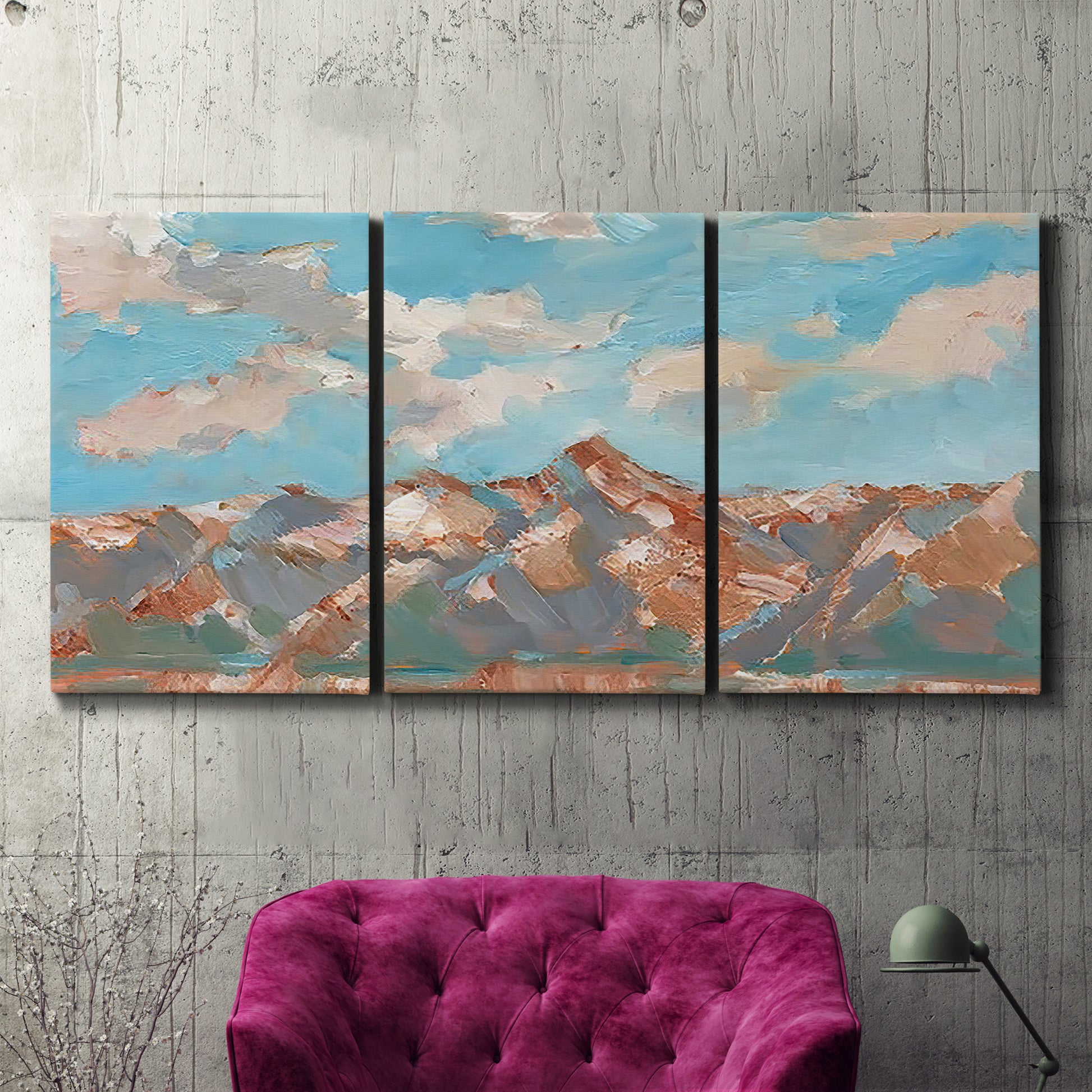Three-panel canvas wall art featuring soft pastel western hills landscape, displayed in a living room above a suede accent chair.