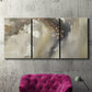 Three-panel canvas wall art featuring flowing abstract wave motion, displayed in a living room above a suede accent chair.
