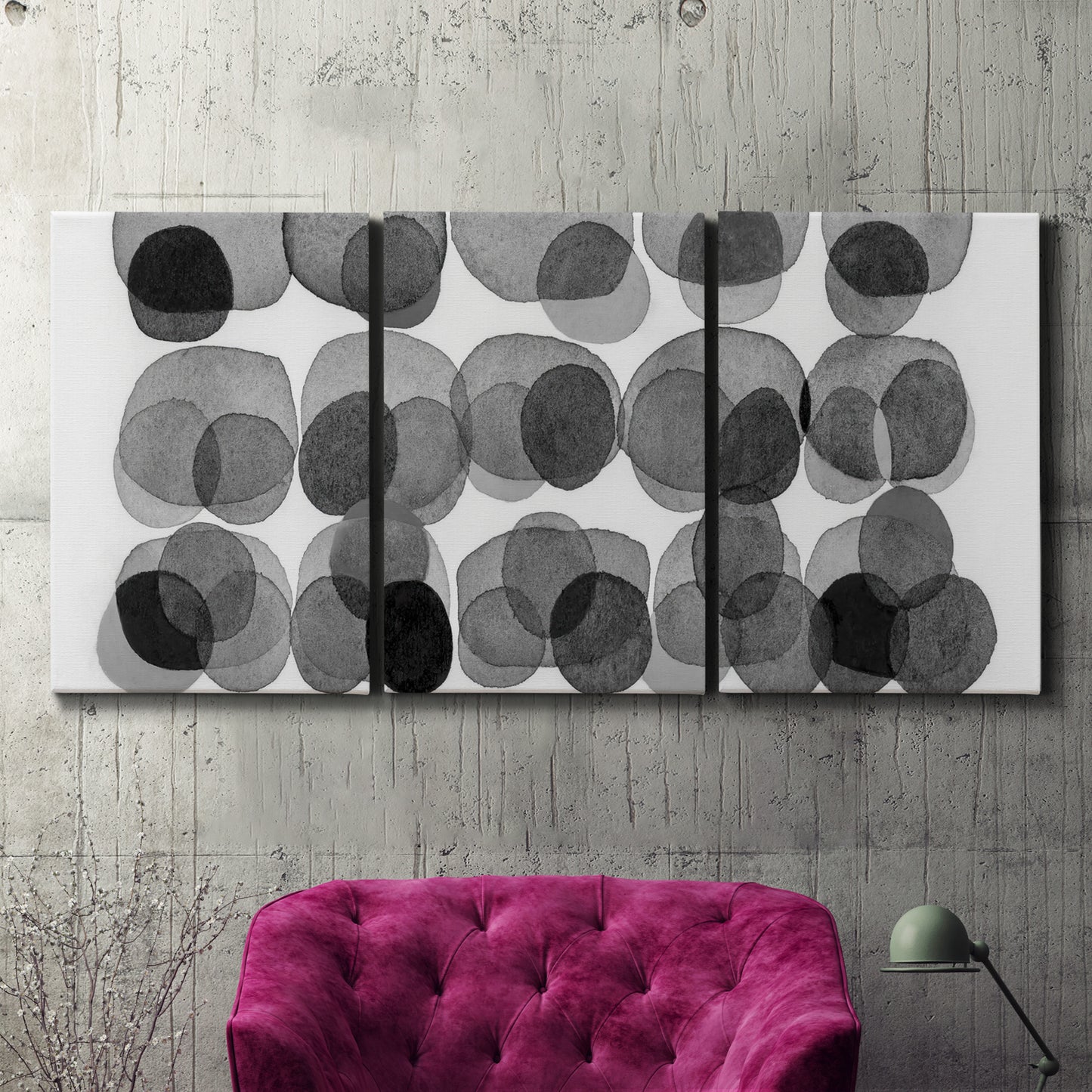 Three-panel canvas wall art featuring geometric abstract watercolor forms, displayed in a living room above a suede accent chair.