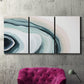 Three-panel canvas wall art featuring abstract coastal shell forms, displayed in a living room above a suede accent chair.