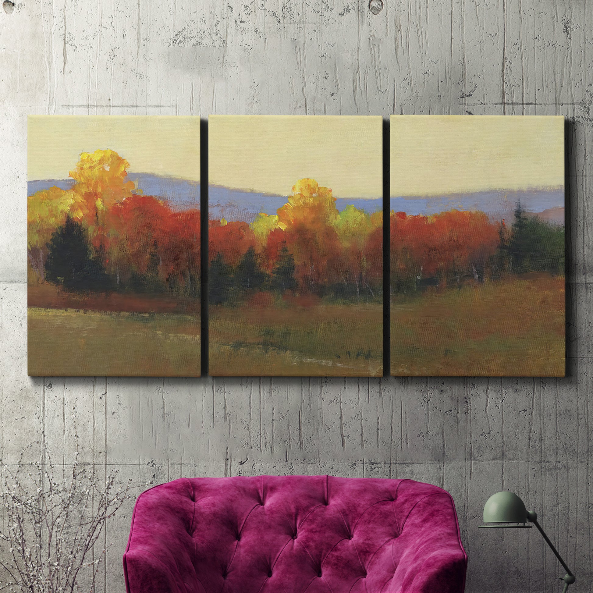 Three-panel canvas wall art featuring autumn landscape changing foliage, displayed in a living room above a suede accent chair.
