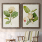 Set of two walnut barnwood framed canvas prints depicting two traditional botanical paintings featuring white magnolia blossoms and glossy green leaves above a sideboard in a cozy sitting room.