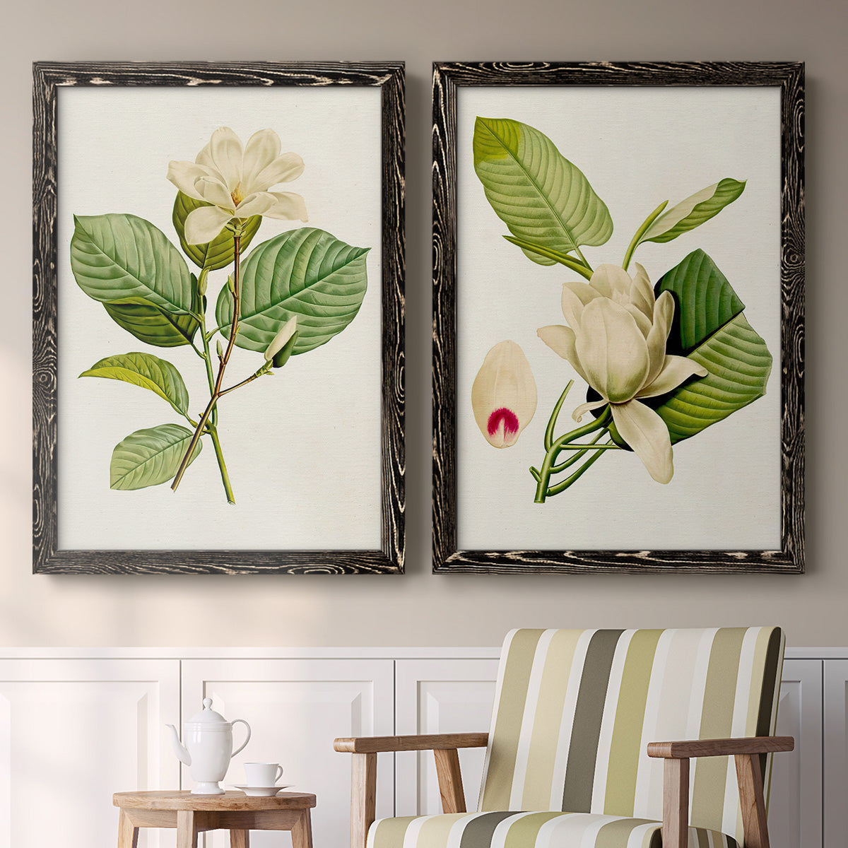 Set of two black barnwood framed canvas prints depicting two traditional botanical paintings featuring white magnolia blossoms and glossy green leaves above a sideboard in a cozy sitting room.