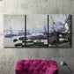 Three-panel canvas wall art featuring working harbor with docked boats, displayed in a living room above a suede accent chair.