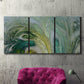 Three-panel canvas wall art featuring layered modern abstract landscape, displayed in a living room above a suede accent chair.