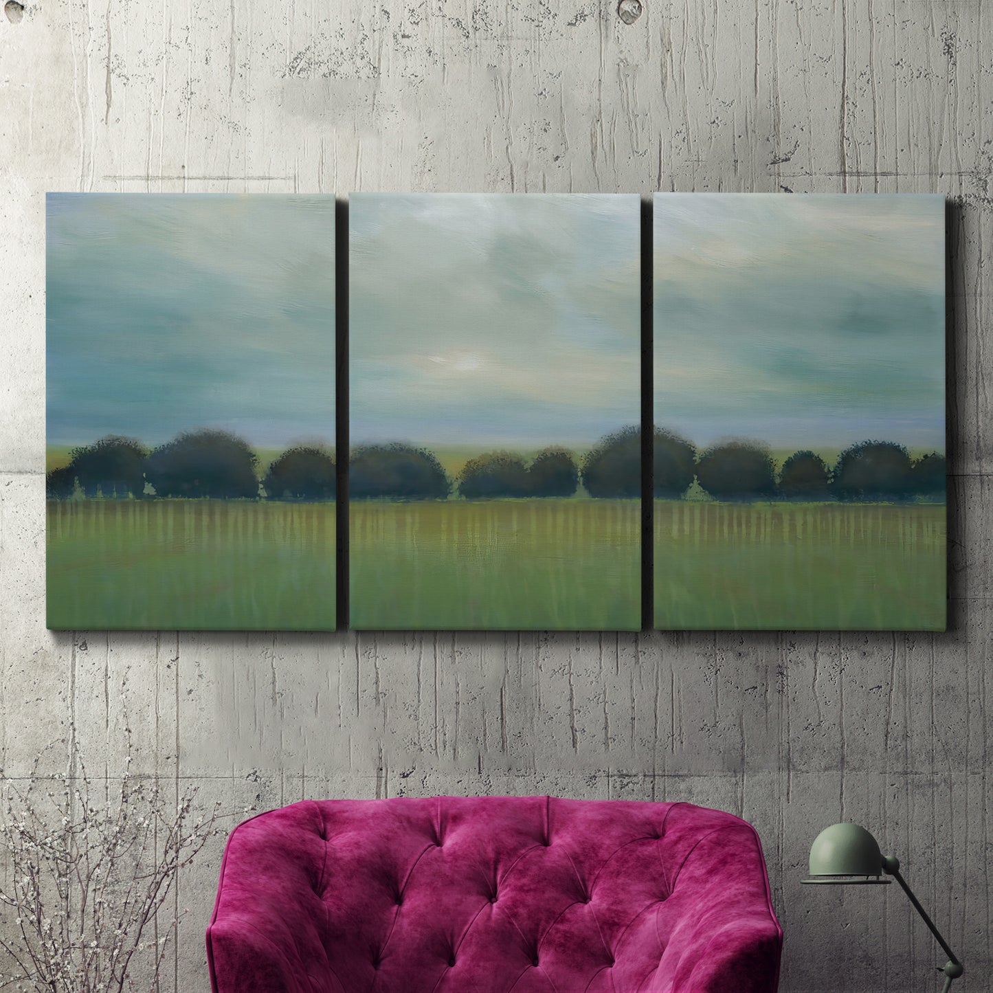 Three-panel canvas wall art featuring rolling green pastoral fields, displayed in a living room above a suede accent chair.
