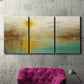 Three-panel canvas wall art featuring warm abstract end of summer palette, displayed in a living room above a suede accent chair.