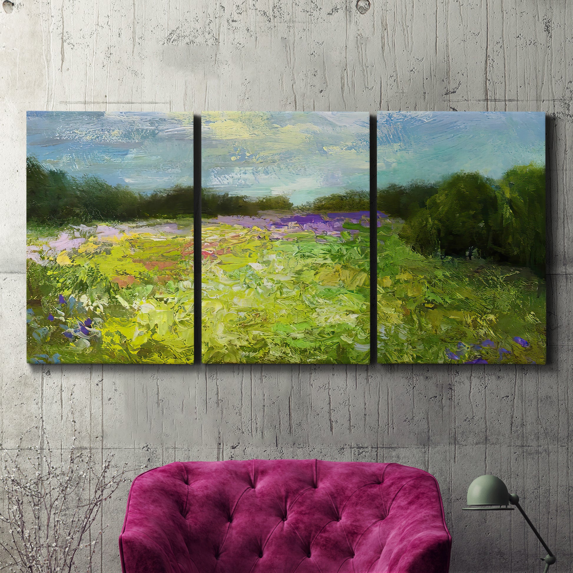 Three-panel canvas wall art featuring pastoral field with wildflowers, displayed in a living room above a suede accent chair.