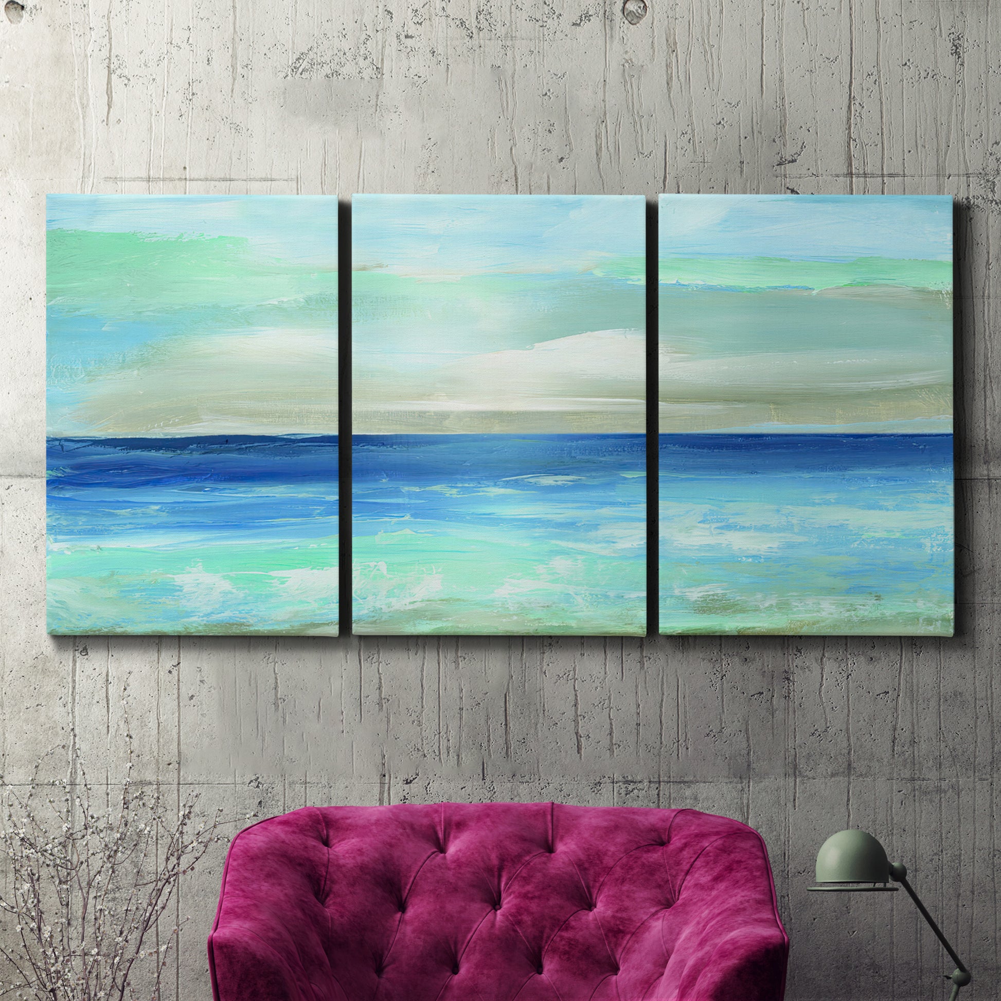 Three-panel canvas wall art featuring vast open blue ocean horizon, displayed in a living room above a suede accent chair.